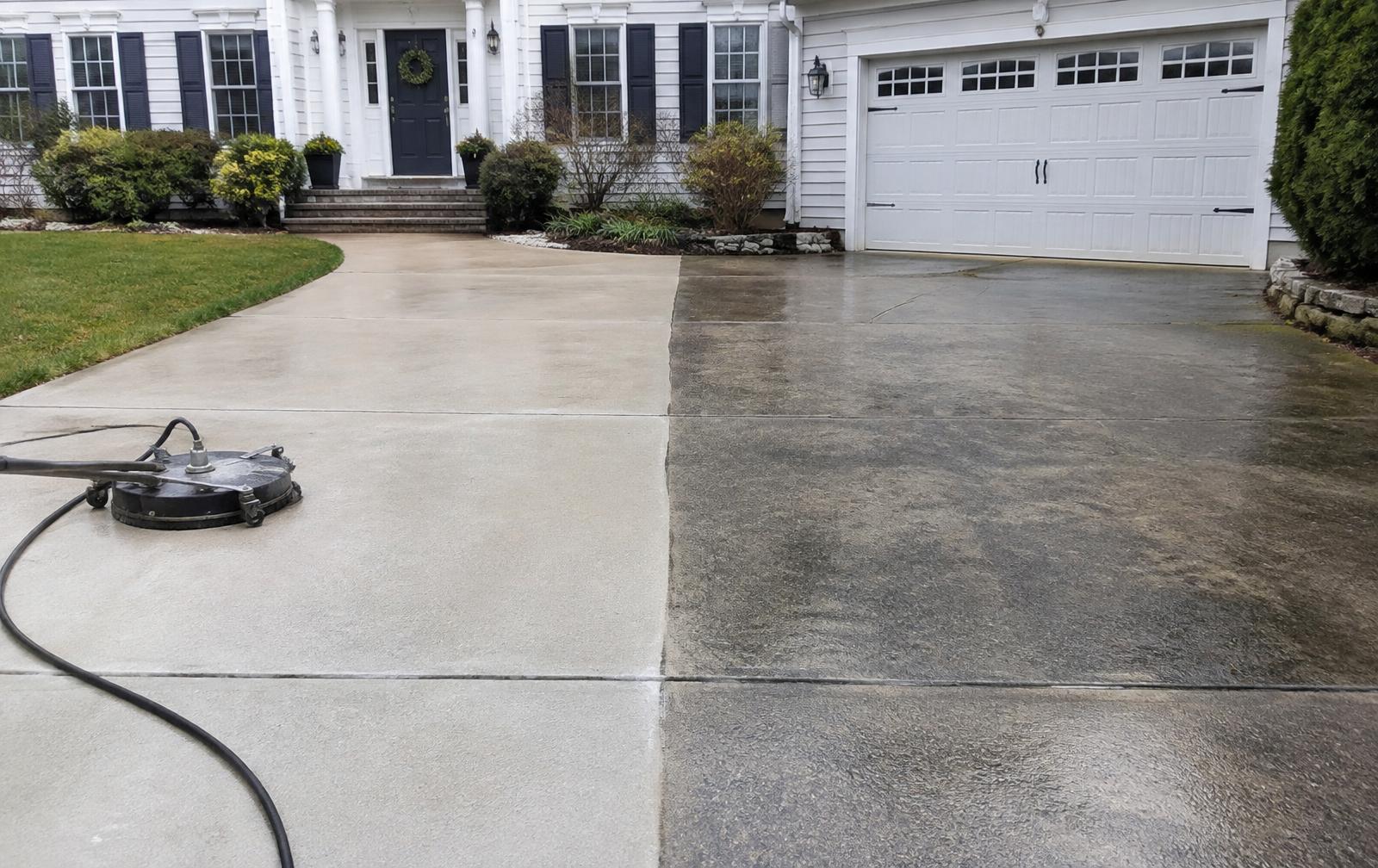 Driveway half cleaned with a surface cleaner, showing the clean line